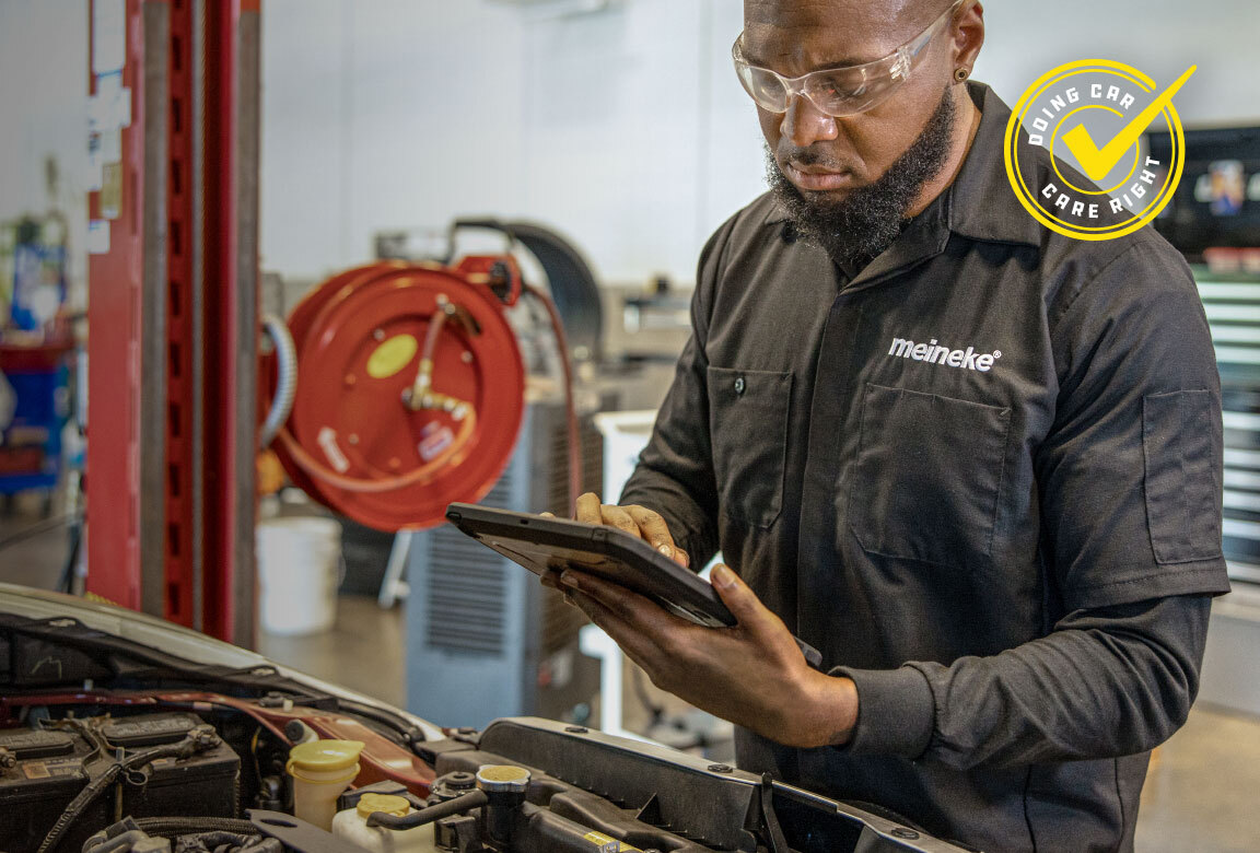 Meineke technician running a digital diagnostic scan on a tablet